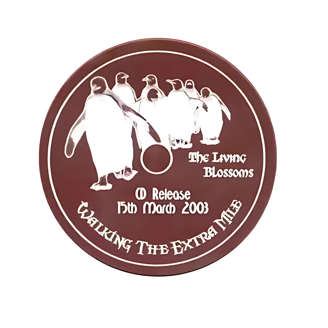 A circular image of penguins in line adorns the cover with text: The Living Blossoms, CD Release 15th March 2008, and Walking the Extra Mile. The maroon backdrop complements like chocolate in a rich symphony. Product Name: CD Chocolate.