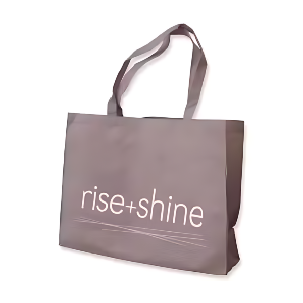 The Non Woven Boutique Bag (Large: 40x55x10 cm) in gray features wide straps and rise + shine text in white, offering a stylish and functional option for everyday use.