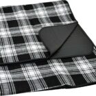 A folded black and white plaid picnic blanket with a black backing. The blanket features a classic checkered design and is neatly arranged to show both the patterned and solid sides.