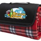A rolled-up red and black plaid blanket with a black flap, featuring the Discovery Island Waterpark logo. The logo includes a mascot with a surfboard, blue waves, and palm trees.