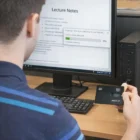 Person copying lecture notes from a Credit Card Usb Memory_1 to a desktop computer in a library.