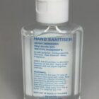 Clear bottle of hand sanitizer with a white cap and blue text label on the front.