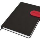 Black notebook with red strap and embossed logo, closed and resting on a white surface.