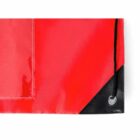 Close-up of a red fabric corner with a black reinforced eyelet and drawstring.