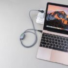 Open laptop with mountain wallpaper, charger connected, on a gray surface.