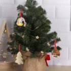Small decorated Christmas tree with star and wooden ornaments, wrapped in burlap at the base.