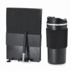 Black notebook, pen, and travel mug with textured grips on a white background.