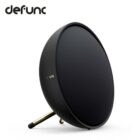 Round black wireless speaker with gold stand and defunc logo on a white background.