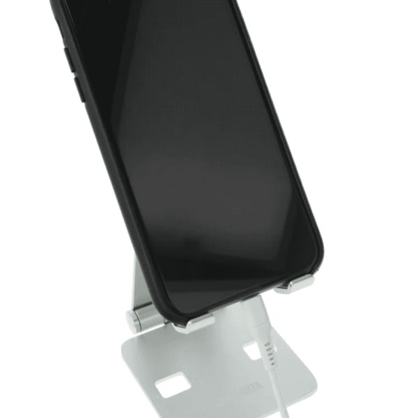 A smartphone on a white stand with a charging cable connected at the bottom.