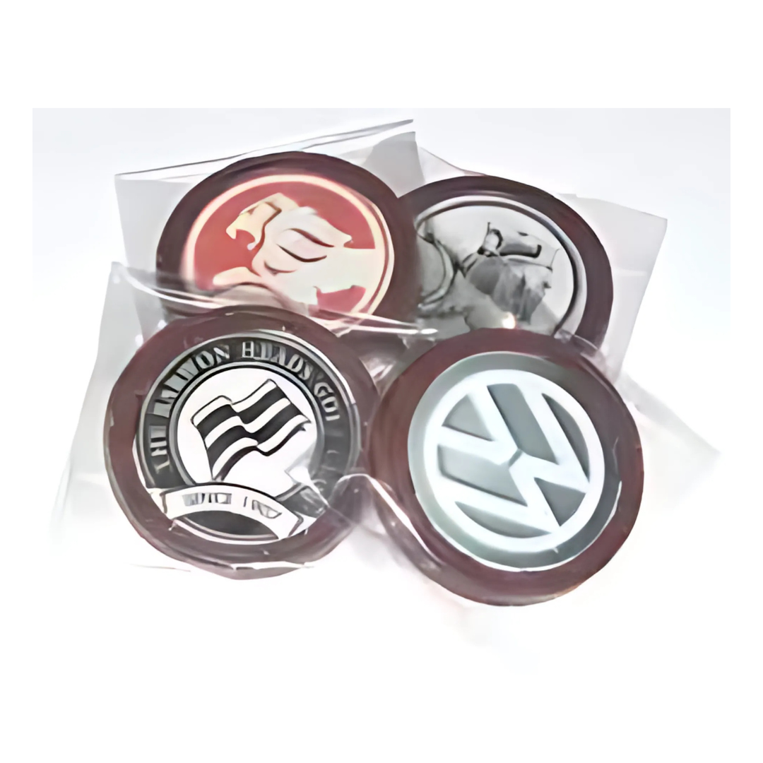 Four car badges are arranged in transparent cases like exquisite Corporate Chocolates Colour Mini Round Cello, with each badge featuring a distinct circular car logo, highlighting the unique branding of each emblem.