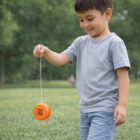 Smiling boy playing with Yo Yo In Colours in a grassy park.