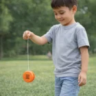 Smiling boy in gray shirt playing outdoors with Yo Yo In Colours.