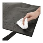 Hand using cloth to wipe water droplets off a black surface.