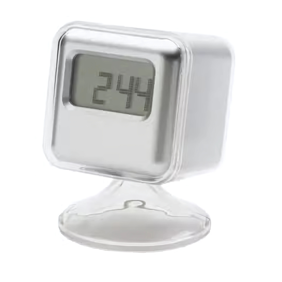 The Cube Clock, a small square digital clock with a silver metallic finish, displays 2:44 while mounted slightly tilted on a transparent stand.