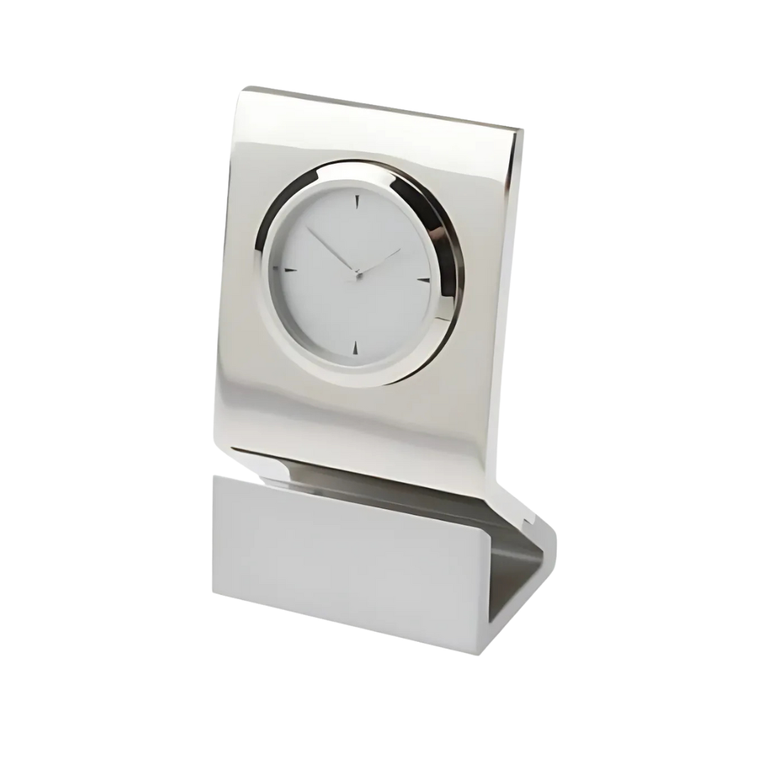 Introducing the Milano Clock: a sleek desk clock featuring a minimalist design with a polished silver finish. It has a round face, thin black hour and minute hands, and an angled rectangular base for added sophistication and style.