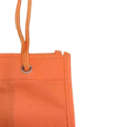Close-up of a corner of the Non-woven Bottle Holder, featuring an orange texture and handle looped through a metal grommet. The fabric has visible stitching for durability, and the top of the handle is slightly frayed.