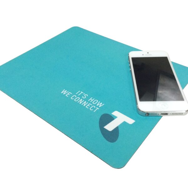 A blue mouse pad with the text Its How We Connect and a stylized T logo. A white smartphone is placed on top of the mouse pad.