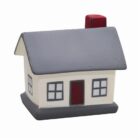 Toy house with grey roof, red chimney, and four windows on a white background.