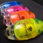 Four colorful capsule-shaped pencil sharpeners arranged in a diagonal row on a black surface.