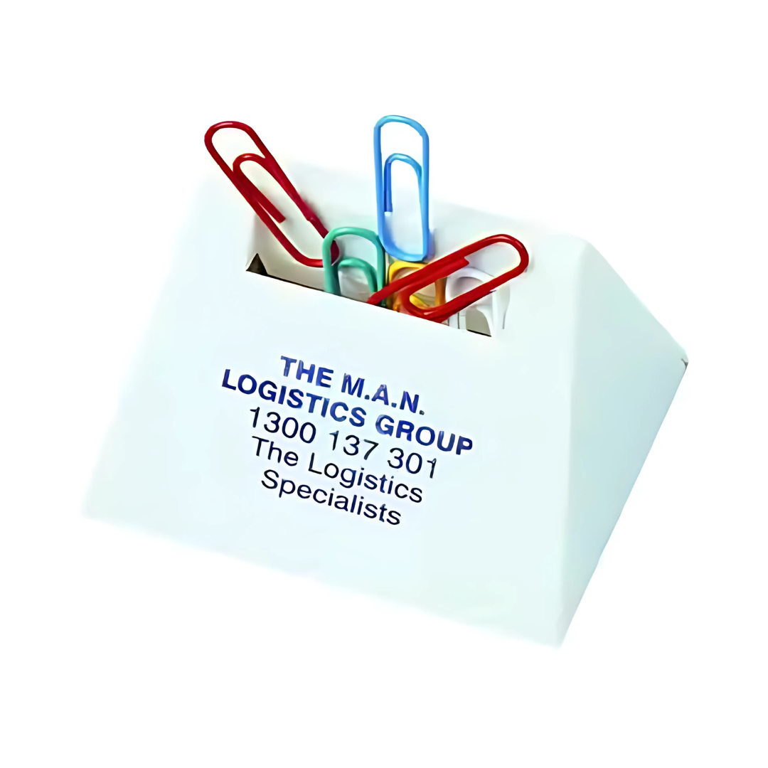 A small white triangular paper clip dispenser labeled THE M.A.N. LOGISTICS GROUP 1300 137 301 The Logistics Specialists holds red, green, and blue paperclips. Product Name: TRIANGULAR PAPER CLIP DISPENSER.