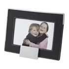 A framed photograph features two smiling children hugging, showcased in the rectangular Troy Picture Frame with a sleek black design, white stitching, and a convenient bottom stand for display.