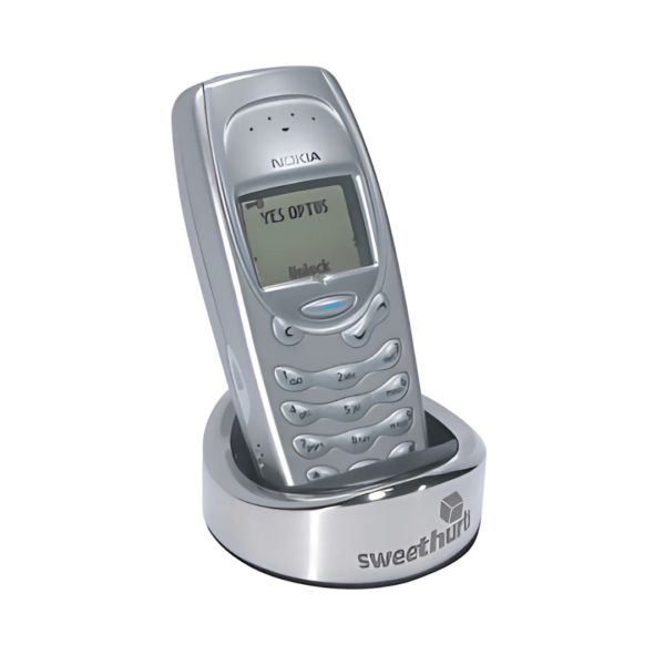 A silver retro-style mobile phone sits on the Valencia Phone Stand, a chic round charging dock. Its screen boldly shows YES OR YES, with sweethut elegantly printed on the base, evoking Valencias artistic charm.