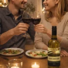 A couple toasts with Hunter Valley Semillon 2009 at a candlelit dinner, bottle on the table.