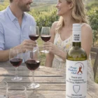 Smiling couple with glasses outdoors, Marlborough Nz Sauvignon Blanc 2009 on the table.