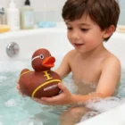 Young boy in a bathtub holding Football Rubber Ducks.