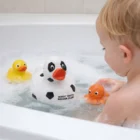 A toddler in a bubble bath plays with Personalised Soccer Duckies and octopus toys.