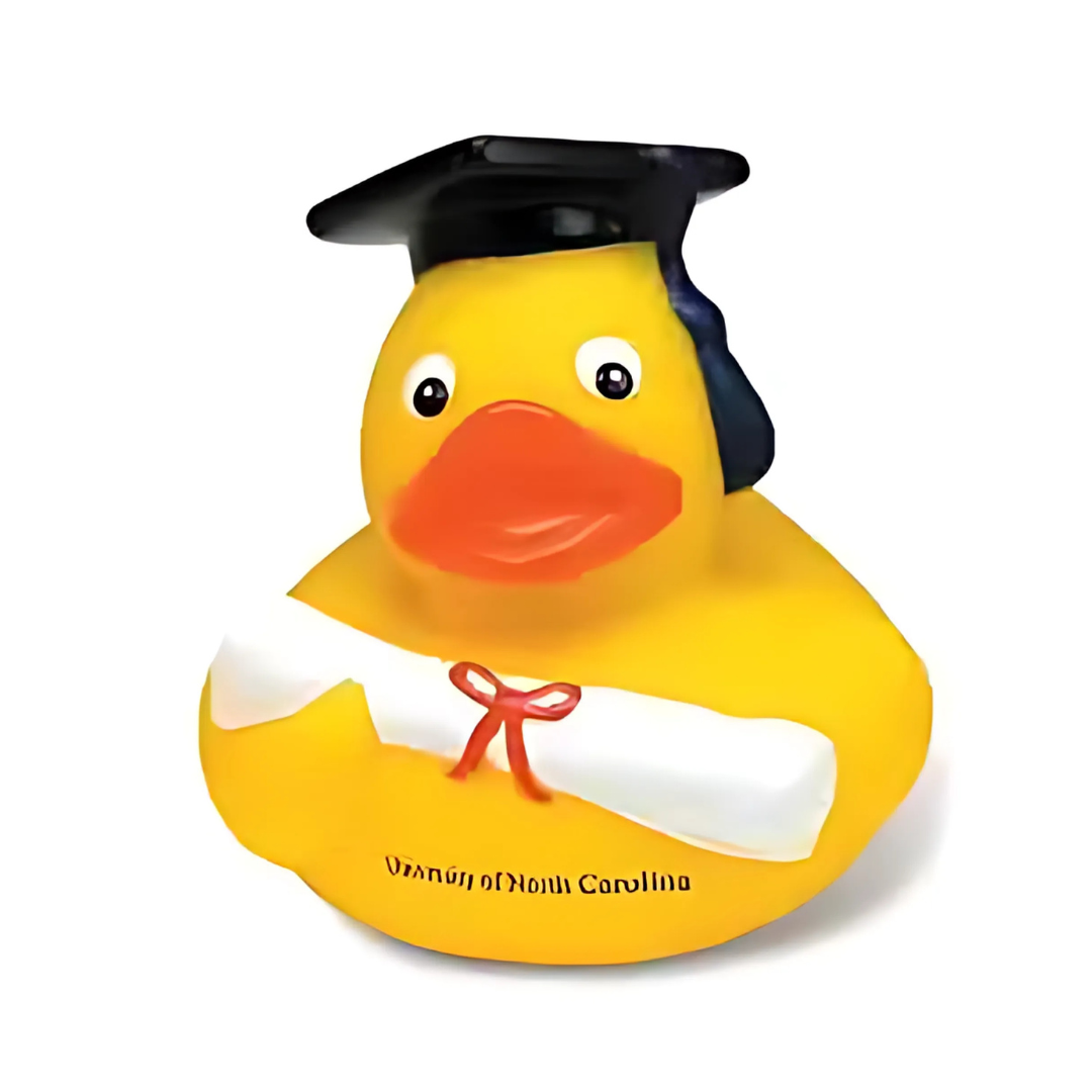 The Custom Graduate Duckie wears a graduation cap and holds a diploma tied with a red ribbon, featuring the University of North Carolina text on its side to celebrate the achievement.