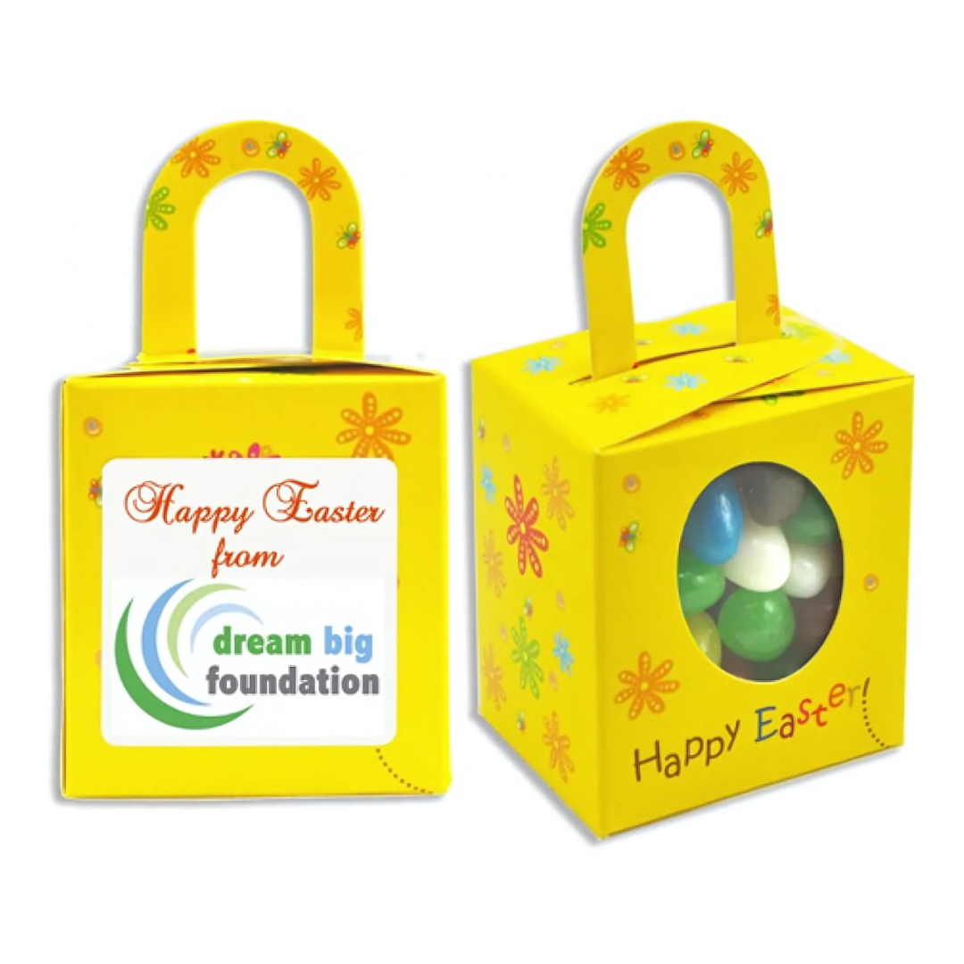 The Branded Easter Chocolate Box features a festive yellow design with Happy Easter from Dream Big Foundation text and colorful flowers. One side has an oval window showcasing green and white candies, complemented by your favorite chocolates, and includes a convenient top handle for easy carrying.