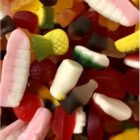Colorful assorted gummy candies in various shapes, including bottles and fruits, close up.
