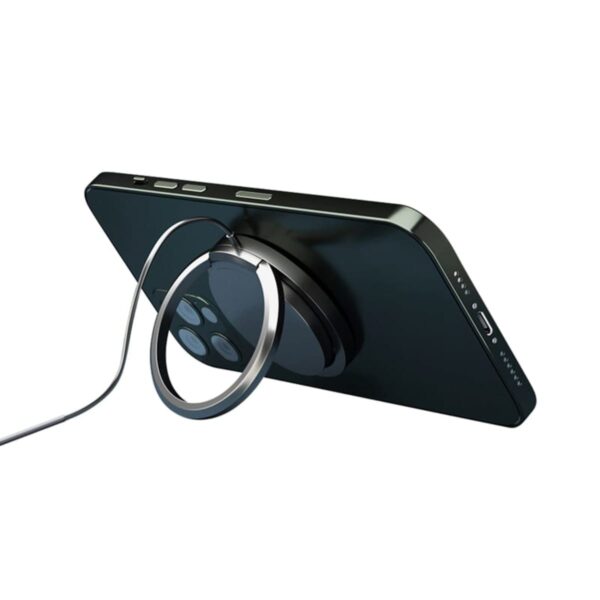 A smartphone with a circular magnetic charger attached to its back is propped up in a horizontal position. The charging cable extends from the charger, and the phones camera lenses are visible.