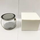 A clear empty paint can with a lid and handle next to a plain white box.