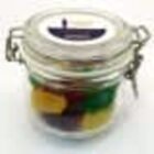 A glass jar with assorted colorful candies and a sealed metal latch on top.