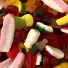 Colorful assorted gummy candies in various shapes, including bottles and fruits, close up.