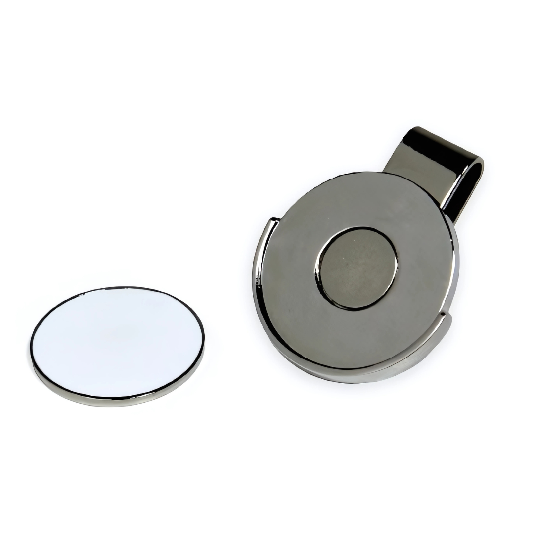 The Golfing Ball Marker Hat Clip is a metallic circular buckle with a reflective finish and central button, positioned next to a white disc with a mirror-like surface. Its perfect for accessorizing or using as a stylish golf ball marker.