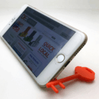 White smartphone on Pembroke Key Phone Stand, website visible on screen.