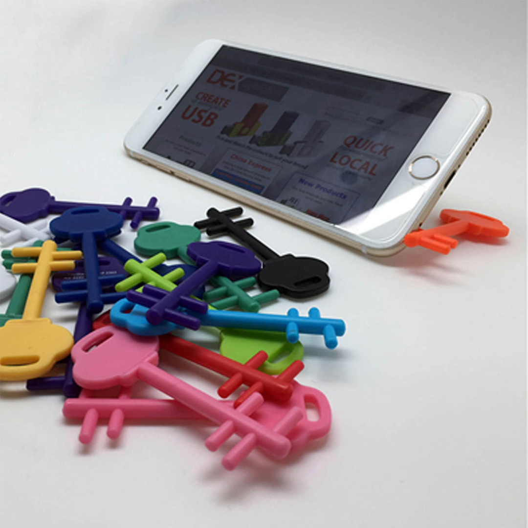 Pembroke Key Phone Stand securely holds your smartphone on any white surface.