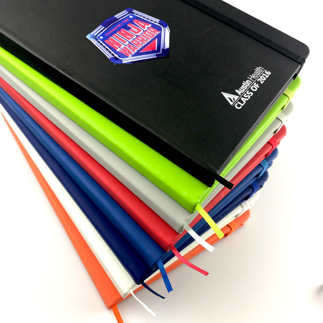 Stack of colorful Rubber feel cover A5 notebooks, top one labeled Ninja Warriors Class of 2016.