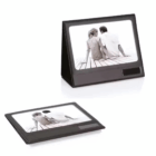 Two people sit on a dock in the Fold up Desk Photo Frame, displayed upright on a desk.