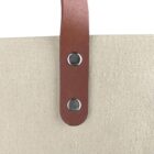 Brown leather strap with two metal rivets attached to beige canvas fabric.