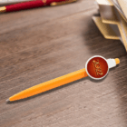 Event Branded Pens With Badge Button on a wooden desk near folders with a 2022 badge attached.