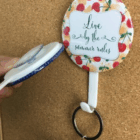 Full Colour Logo Button Badge Hangers with Live by the summer rules on corkboard style.
