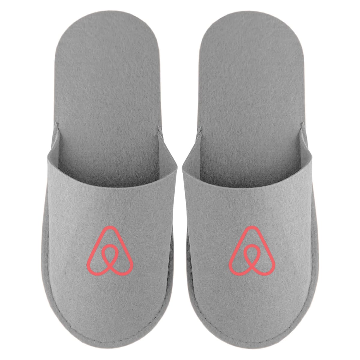 A pair of gray slippers with a red Airbnb logo on each slipper.