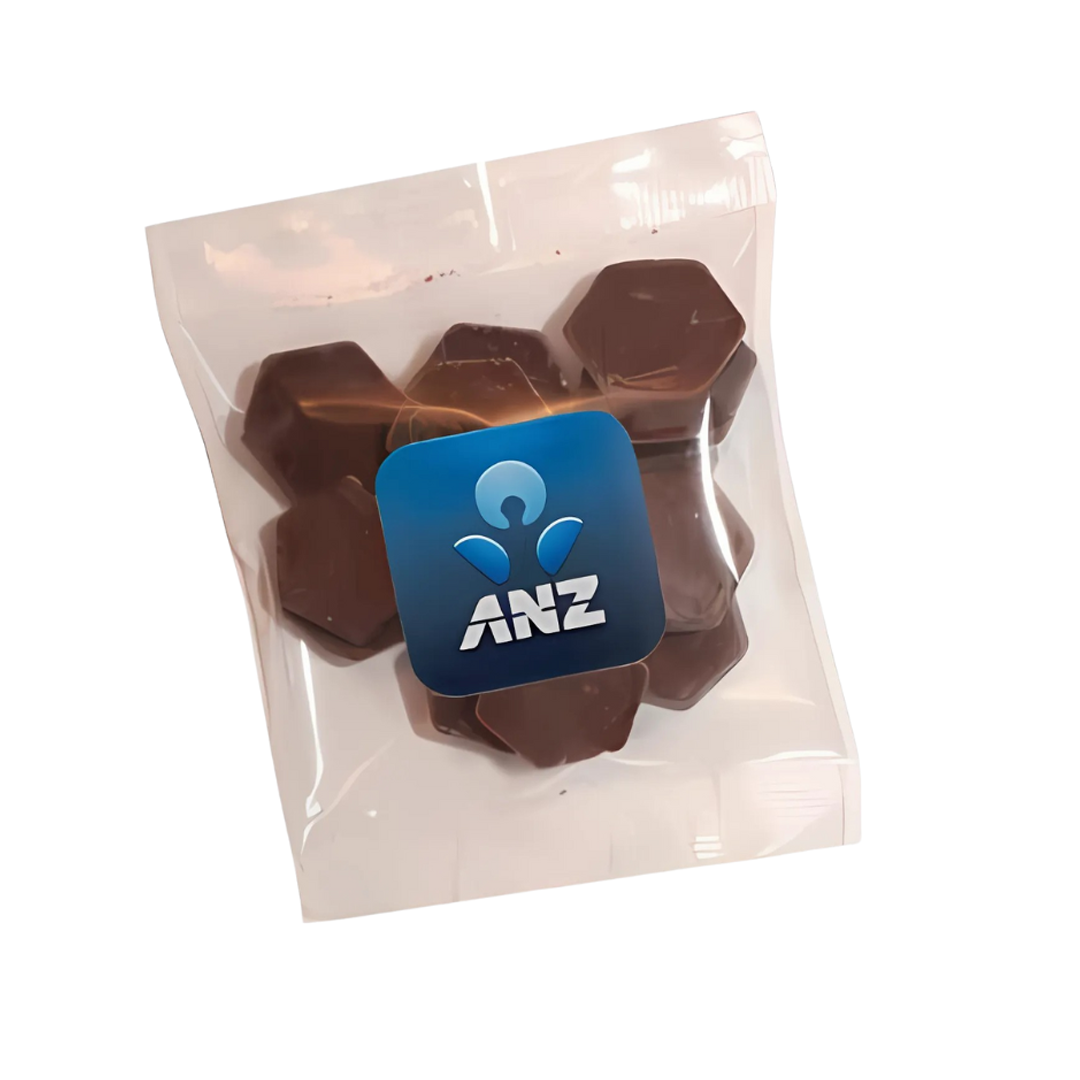 A transparent plastic bag containing hexagonal Lindt Melting Chocolate pieces, sealed with a blue ANZ logo sticker. This 30g treat is perfect for any occasion.