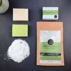 A package of Logo Branded Natural Bath Salts, two soap bars, and bath crystals on a dark surface.