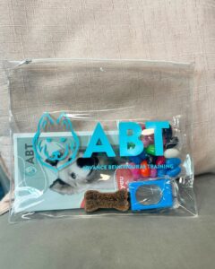 Clear zip pouch printed with the ABT Advance Behavioural Training logo, filled with dog training treats and accessories