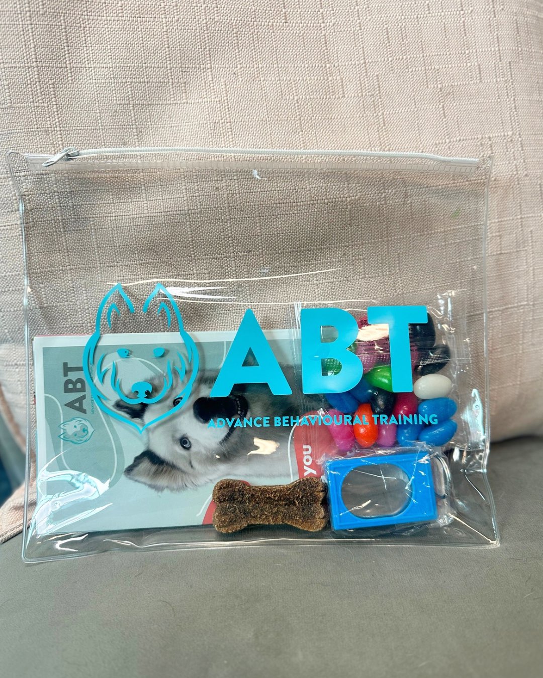 Clear zip pouch printed with the ABT Advance Behavioural Training logo, filled with dog training treats and accessories